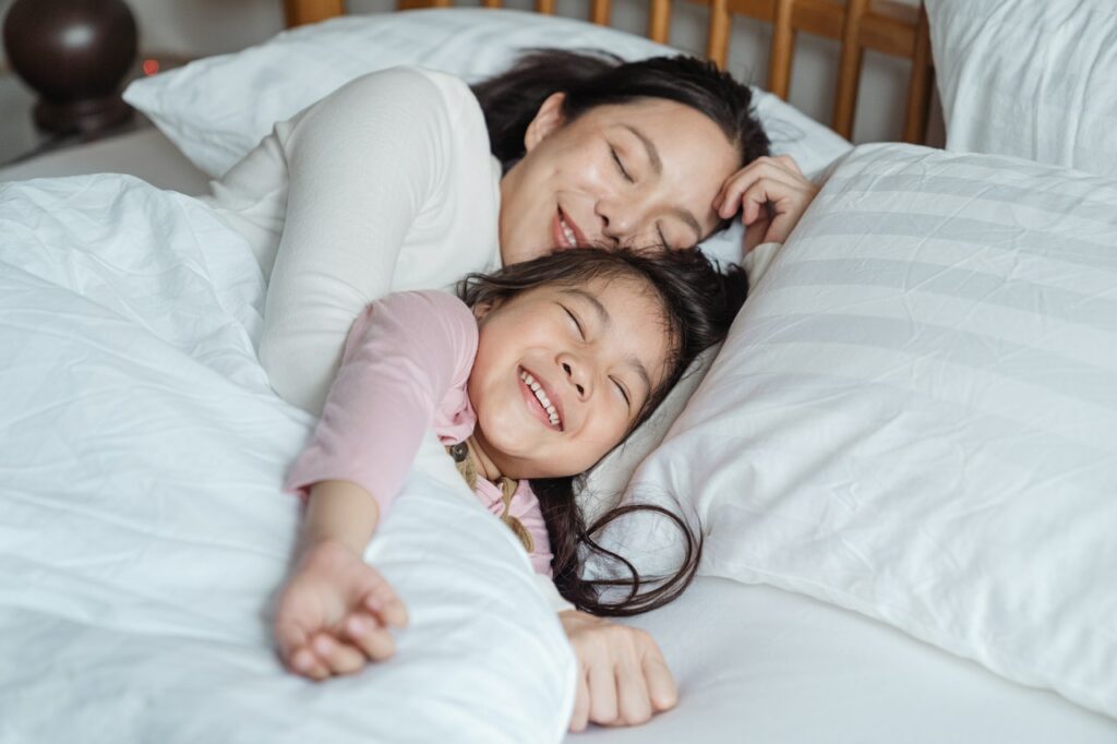 mere et enfant riant dans des draps blancs