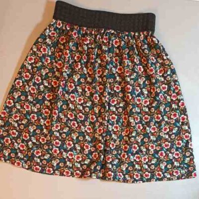 Jupe courte Kate, Les créatives Dinan dans un imprimé fleuri et une ceinture fantaisie élastiquée. Vue posée à plat,kitac,made in france,box couture,box cadeau,box prêt-à-coudre,box pret a coudre,apprendre à coudre,couture debutant,machine a coudre,savoir coudre,box mode,box vetement,jupe à coudre,jupe a coudre,jupe diy,diy jupe,coudre,couture,viscose